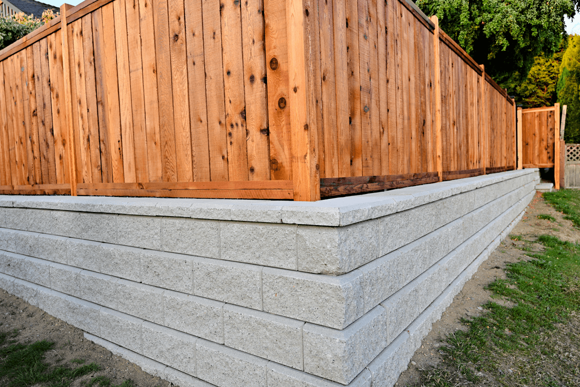 Grey stone retaining wall with wooden fence on top